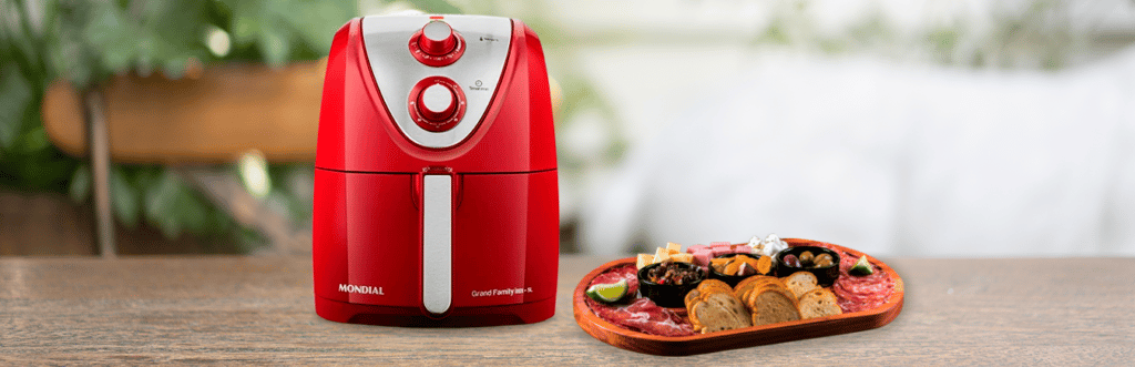 air fryer em cima da mesa com um prato de petiscos ao lado