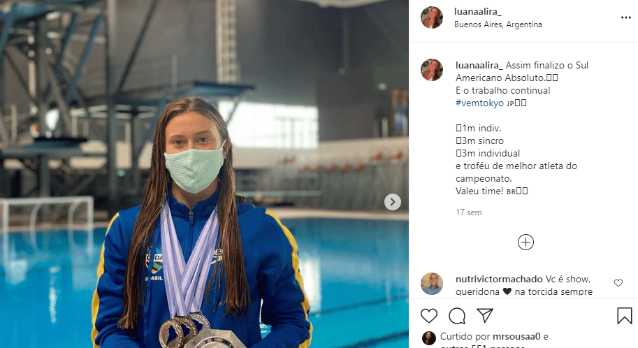 Atleta Luana Lira em frente a uma piscina mostrando suas medalhas