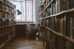 Mulher lendo e estantes de livros organizados nas laterais