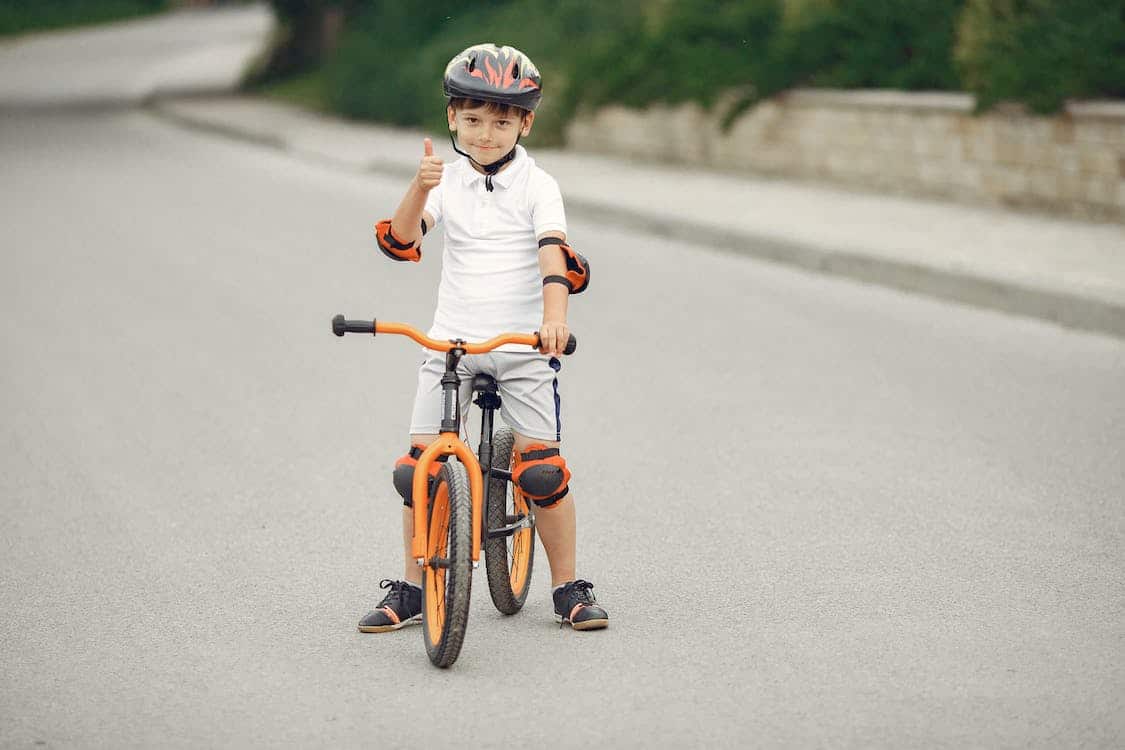 criança em bicicleta infantil com equipamentos de segurança