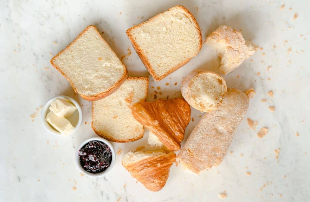 Fotografia de pães, croissant, geléia e manteiga