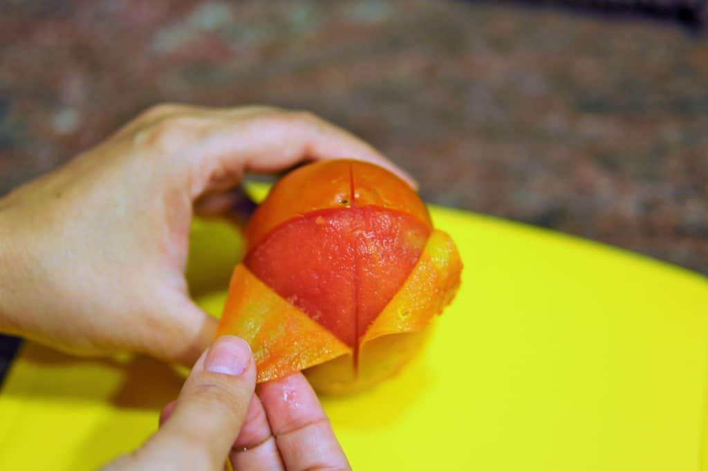 Fotografia de pessoa tirando a pele de tomate