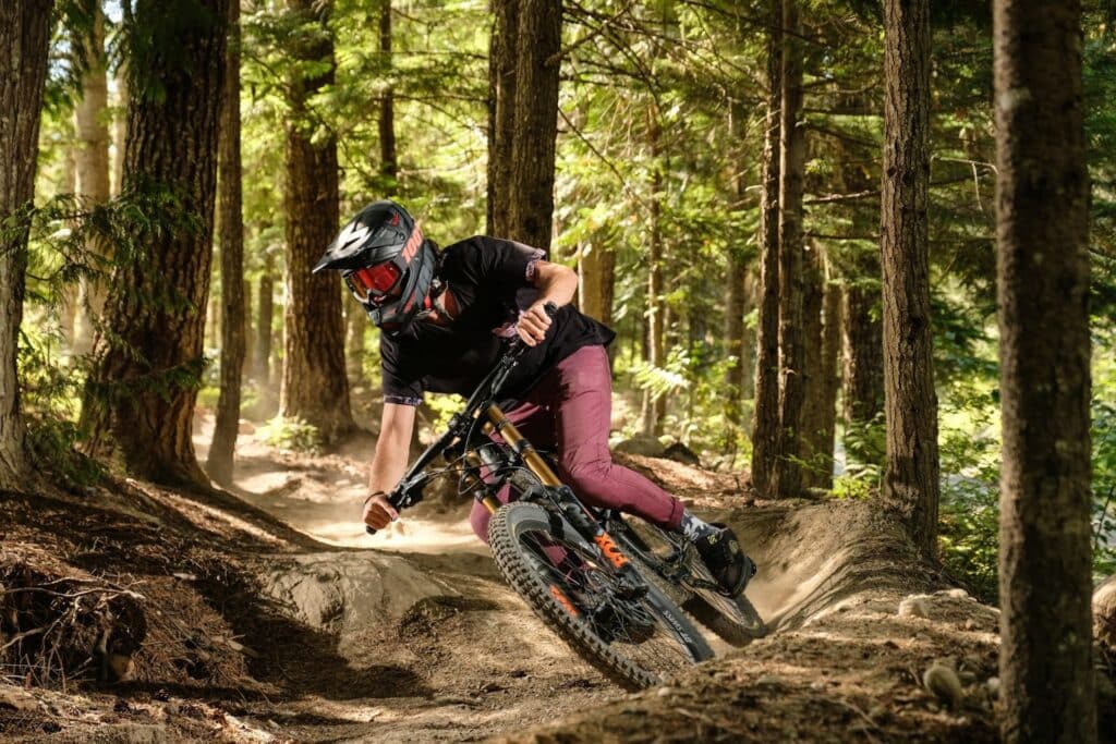 Fotografia de cross bike e ciclista de capacete e óculos em trilha na floresta