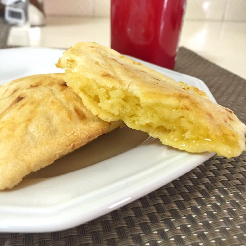 Fotografia de sancuíche cortado ao meio e copo de suco ao fundo