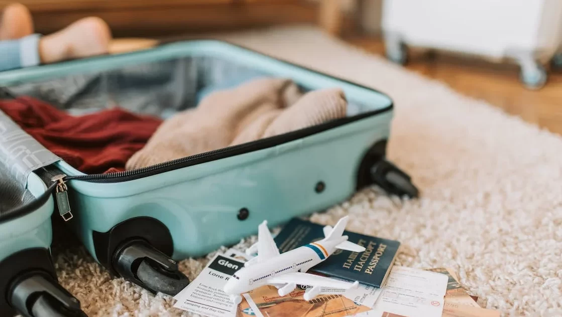 Mala de bordo em cima da cama com itens para viagem