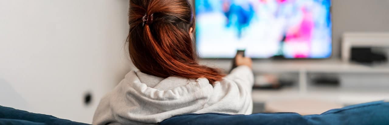 mulher em frente a TV apontando o controle remoto