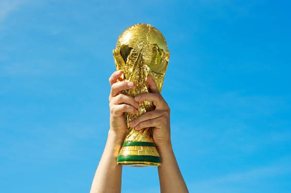 Mãos erguem taça do campeonato de futebol mundial