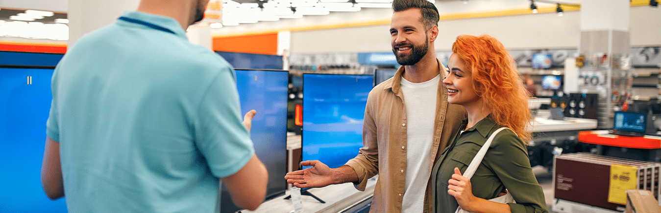 Casal em uma loja escolhendo uma smart tv com um vendedor